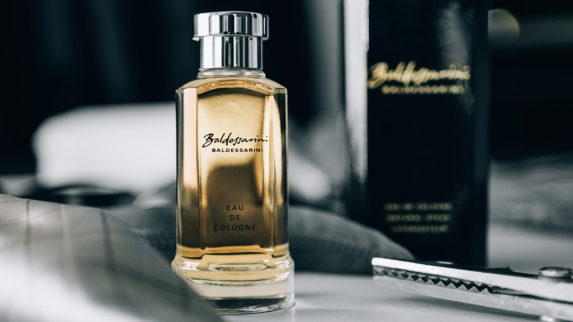 Baldessarini Classic Eau de Cologne Flakon mit Herrenpflege im Hintergrund